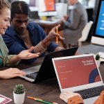 Equipe diversa colabora com laptops em um escritório moderno voltado à inovação digital.