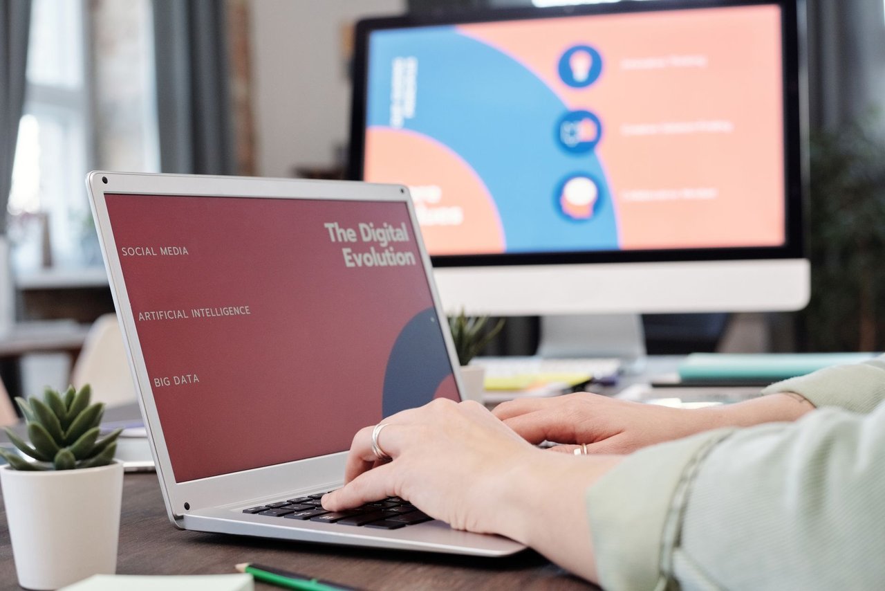Profissional trabalha em um laptop em um escritório moderno, diante de uma tela com elementos visuais de evolução digital.