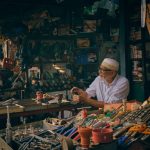 Comerciante organiza ferramentas em uma loja movimentada.